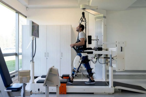 Patient in physical therapy doing exercises with an exoskeleton at the hospital - healthcare and medicine concepts. Design on screen was made from scratch by us